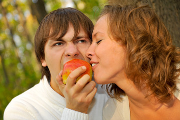 Loving couple eating apple in the park