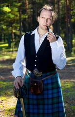 Fototapeta premium Man in scottish costume with sword and pipe