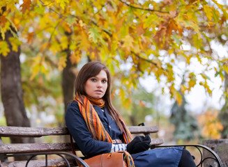 Obraz na płótnie Canvas Young woman sitting on the bench