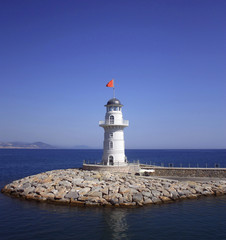 White beacon near coast with a red flag