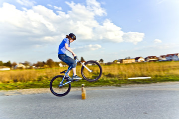 young boy jumping with his dirk bike over a barrier at the stree