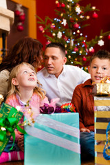 Fototapeta na wymiar Weihnachten - Familie mit Geschenken am Weihnachtsabend