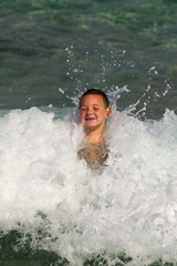 kleiner Junge schwimmt durch Wellen