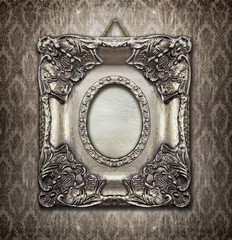 Ornamental silver frame on an aged damask wallpaper