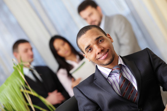 Happy african-american businessman with his team working behind