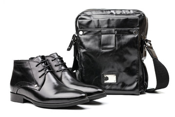 Naklejka premium Pair of black men boots and messenger bag over white