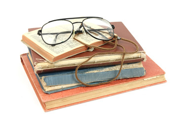 Glasses and open dictionary lying on a pile of old books