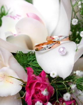 Wedding gold rings lie on a bunch of flowers for the bride