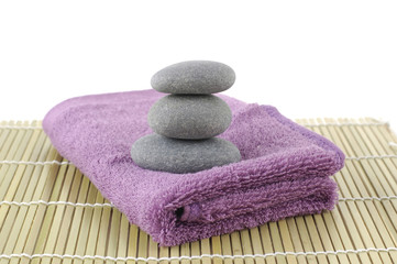 Fototapeta na wymiar stones in balance on pink towel on bamboo stick straw mat