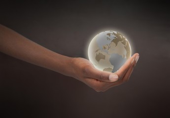 Feminine hand holding a glowing planet globe