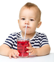 Cute little boy is drinking red juice
