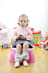 little girl sitting on the potty - obrazy, fototapety, plakaty