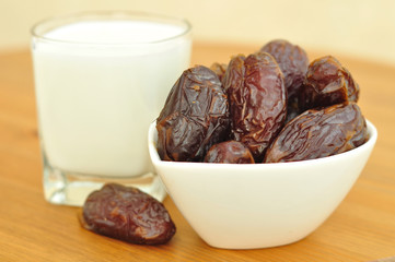 Medjoul dates and a glass of milk on a wooden table.  