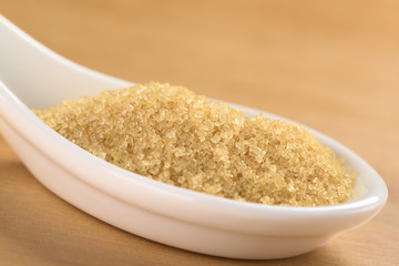 Brown granulated cane sugar on ceramic spoon
