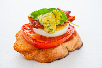 A baguette slice with tomato egg bacon and herb butter