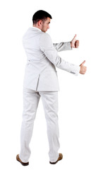 Back view of young business man in white suit going thumb up