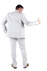 Back view of young business man in white suit going thumb up