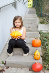 little, caucasian girl holding pumpkin in her hands