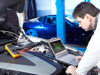 Motor mechanic is tuning and checking the engine of a car