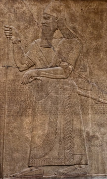 Ancient assyrian clay relief depicting a warrior with a sword