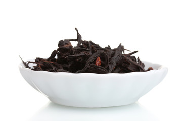 Black dry tea leaves in plate isolated on white