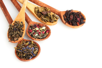 Different kinds of green and black dry tea in woooden spoon