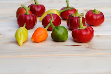 hot chili peppers of different colors on wooden cutting board