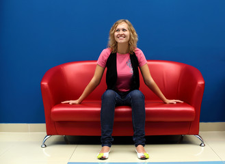 Fototapeta na wymiar Young woman sitting on red sofa