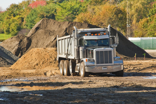 A dump truck about to unload a pile of dirt