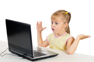 Little girl with a surprised face is on the computer