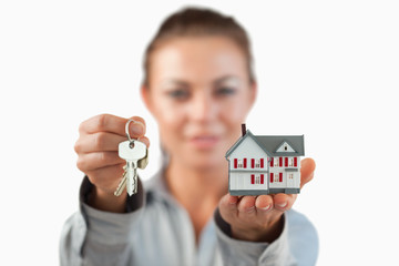 Miniature house and keys being presented by female estate agent