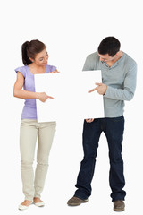 Young couple pointing at sign they are holding together