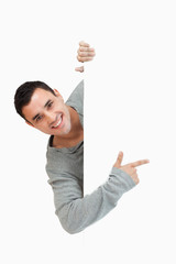 Smiling young male pointing around the corner