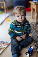 Fototapeta na wymiar Little toddler boy with blue eyes playing motorcycle