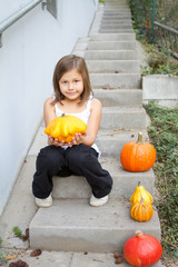 little, caucasian girl holding pumpkin in her hands