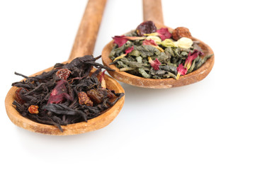 Green and black dry tea leaves in woooden spoons