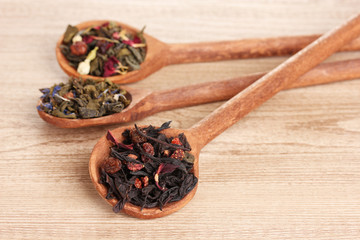 Different kinds of green and black dry tea in spoons