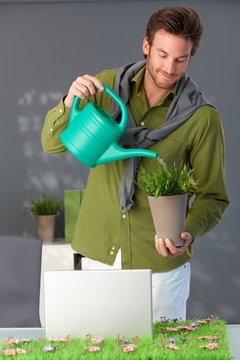 Handsome man watering plant at home