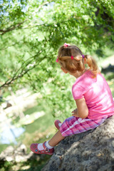 Naklejka premium Little girl sitting in the park, backview