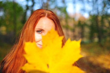 red-haired woman with a yellow leaf - obrazy, fototapety, plakaty