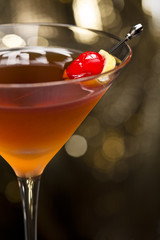 Manhattan cocktail garnished with a cherry and lemon