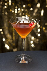 Manhattan cocktail garnished with a cherry and lemon