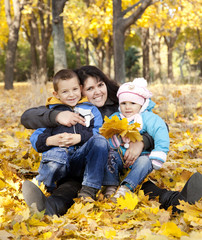 Fototapeta premium Mother and her childrens are playing in autumn park