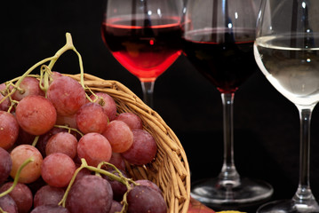 Cesto con uva e calici di vino su sfondo nero 2