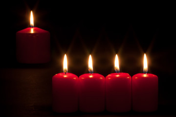 Set of red candles burning in the dark