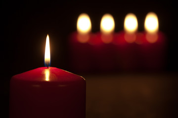Set of red candles burning in the dark with selective focus