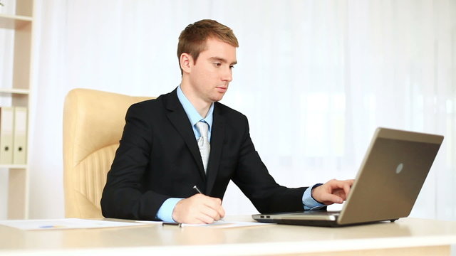 Businessman working in an office looking at camera.