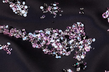 Diamond (small purple jewel) stones heap over black silk cloth b