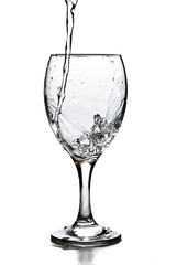 Water pouring into the glass over white background