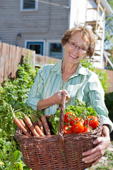 Senior woman holding basket full of vegetables